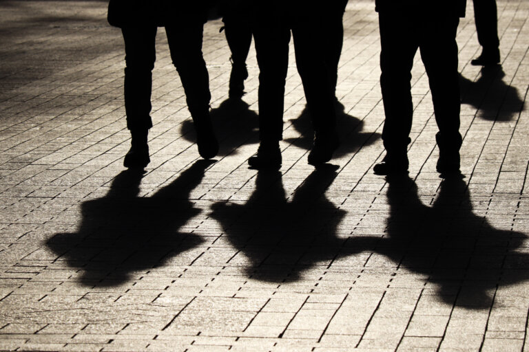 Crowd walking down on sidewalk, concept of strangers, crime, society, epidemic, population battery sombathy law firm