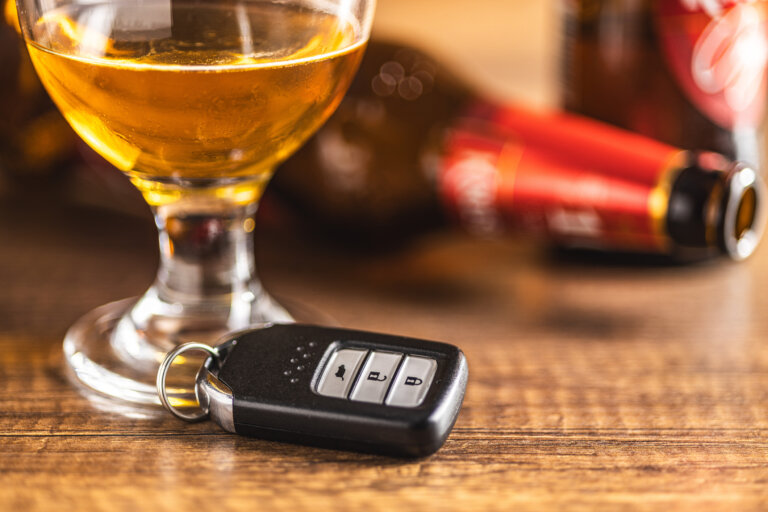 Car key with beer glass on a wooden table. Booze driving concept. Drunk driver concept. DUI sombathy law firm