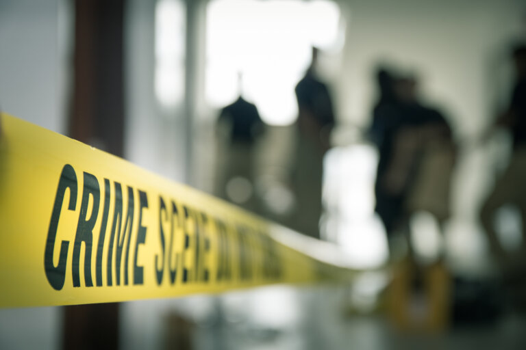 crime scene tape with blurred forensic law enforcement background in cinematic tone and copy space assault somabthy law