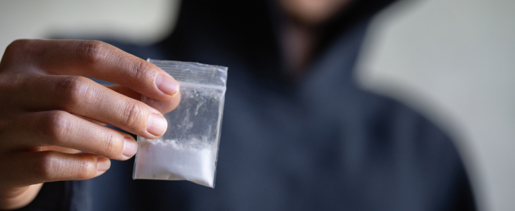 Person holding clear bag of powder drugs