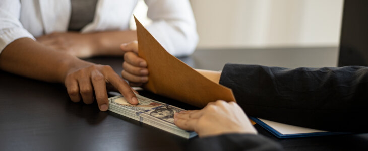 man sliding a stack of money across the table to a woman