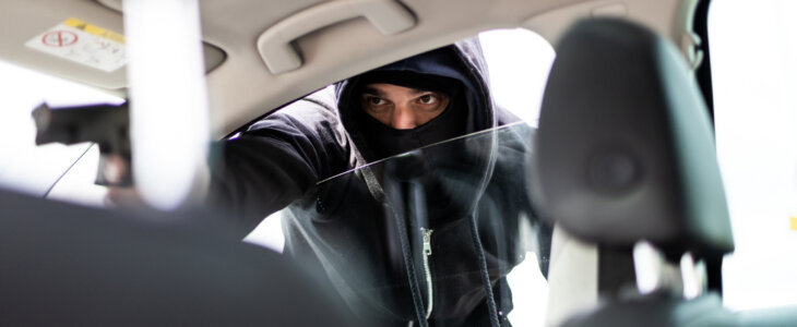 Man in black mask with a gun carjacking a vehicle