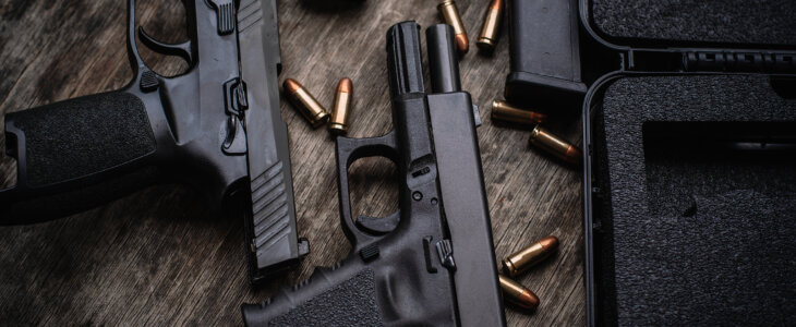 Two 9mm pistols hold slides on a wooden table.