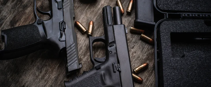 Two 9mm pistols hold slides on a wooden table.