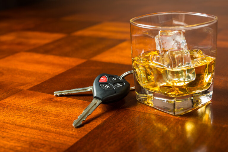 Car keys with glass of whiskey on table, drinking and driving