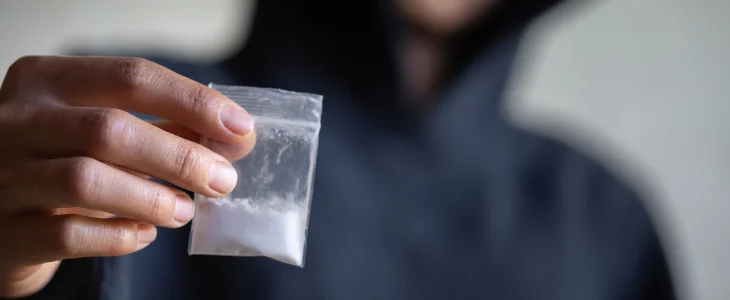 Person holding clear bag of powder drugs